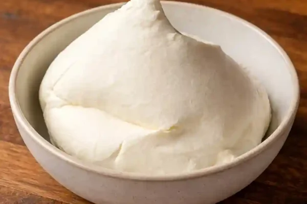 Domaći mascarpone sir kremaste teksture poslužen u bež keramičkoj zdjeli na tamnoj drvenoj podlozi Internacionalno Italijanska Kuhinja Domaći mascarpone sir – Kremast i savršen kao iz trgovine 9 veljače, 2026 0 Comment Idi na recept Preuzmi recept Ako želiš domaći mascarpone sir koji je kremast, stabilan i pouzdan u svakom receptu, ova provjerena metoda pokazuje kako ga napraviti kod kuće bez kompliciranih sastojaka. Mascarpone je jedan od onih sireva koji se često koristi, ali se rijetko priprema kod kuće. Ipak, domaći mascarpone sir može se napraviti vrlo jednostavno, uz nekoliko osnovnih sastojaka i malo strpljenja. Rezultat je bogata, glatka i maziva tekstura koja se ponaša gotovo identično kao kupovni mascarpone. Ova metoda temelji se na kontroliranom zagrijavanju slatkog vrhnja i zgrušavanju pomoću limunova soka, što je klasičan i provjeren postupak u kućnoj izradi svježih sireva. Dodavanje male količine mlijeka u prahu pomaže postići puniju strukturu i stabilnost, što je posebno važno ako mascarpone planiraš koristiti za tiramisu, kremaste kolače ili fine deserte u čaši. 📌 Sadržaj članka U ovom vodiču pronaći ćeš sve važne informacije o pripremi domaćeg mascarpone sira, od provjerenog recepta do savjeta koji osiguravaju savršenu teksturu i pouzdan rezultat. 👉 Domaći mascarpone sir – provjeren recept za savršenu teksturu 👉 FAQ – Često postavljana pitanja 👉 Najčešće greške kod pripreme i kako ih riješiti 👉 Razlike između domaćeg i kupovnog proizvoda 👉 Kako odabrati pravo slatko vrhnje za domaći mascarpone sir Domaći mascarpone sir ima dugu tradiciju u talijanskoj kuhinji, gdje se koristi kao baza za brojne deserte i kreme. U kućnoj verziji dobiva se vrlo sličan proizvod, neutralnog okusa i ugodne mliječne note, koji se lako prilagođava daljnjoj upotrebi. Upravo zato je ovaj recept praktičan izbor za sve koji žele pouzdanu alternativu kupovnom mascarponeu, bez kompromisa u kvaliteti. U nastavku slijedi jasno strukturiran recept, s točnim mjerama i koracima, prilagođen za siguran rezultat i dosljednu teksturu. Ako se pravilno pripremi i čuva, ovaj domaći mascarpone sir može se koristiti u širokom rasponu recepata, od klasičnih do modernih slastica. Što je domaći mascarpone sir? Domaći mascarpone sir je kremasti svježi sir blagog okusa koji se priprema od slatkog vrhnja uz jednostavan postupak zagrijavanja i cijeđenja. Ne zahtijeva pečenje niti posebnu opremu, već samo malo vremena i strpljenja za postizanje prave teksture. Najčešće se koristi kao baza za deserte poput tiramisua, torti, kolača u čaši i raznih krema. Zbog svoje neutralnosti lako se prilagođava i slatkim i blagim slanim kombinacijama. Upravo zato je domaći mascarpone sir praktično rješenje kada želiš pouzdan sastojak za provjerene recepte. Zašto ovaj recept funkcionira? Uravnotežen omjer sastojaka omogućuje pravilno zgrušavanje i punu, kremastu strukturu bez dodatnih stabilizatora. Kontrolirana obrada daje dosljedan rezultat koji se lako ponavlja i kod kućne pripreme. Jasan i logičan slijed procesa osigurava stabilnu teksturu bez rizika od razdvajanja. Prilagođen kućnim uvjetima, bez potrebe za posebnom opremom ili rijetkim sastojcima. Može se pripremiti unaprijed, što ga čini praktičnim izborom za planiranje deserata i kolača. Domaći mascarpone sir kremaste teksture poslužen u keramičkoj zdjeli na drvenoj podlozi Domaći mascarpone sir – kremasta tekstura Domaći mascarpone sir – provjeren recept za savršenu teksturu: Domaći mascarpone sir kremaste teksture poslužen u keramičkoj zdjeli na drvenoj podlozi Domaći mascarpone sir Nema ocjena Domaći mascarpone sir je kremasti svježi sir neutralnog okusa koji se jednostavno priprema od slatkog vrhnja uz postupak zagrijavanja i cijeđenja. Ova verzija daje stabilnu i glatku teksturu, idealnu za tiramisu, kolače, kreme i deserte u čaši. Recept je pouzdan, lako ponovljiv i prilagođen kućnoj pripremi. Porcije 800 gr Priprema 15minutes mins Vrijeme kuhanja 5minutes mins Hlađenje Vrijeme hlađenja i cijeđenja 12minutes mins Ukupno vrijeme 12hours hrs 20minutes mins Preuzmi recept Spremi na Pinterest Sastojci 1x 2x 3x 1 l Slatko vrhnje za šlag (min. 35 % m.m.) 6 žlica Limunov sok 1 žlica Šećer 4 žlice Mlijeko u prahu (po želji, pogledaj napomene) Priprema U loncu pjenjačom pomiješajte slatko vrhnje, šećer i mlijeko u prahu (ukoliko stavljate). Zagrijavajte na srednje jakoj vatri uz stalno miješanje. Kada smjesa dosegne 82 °C, održavajte temperaturu između 82–87 °C tijekom 5 minuta, stalno miješajući silikonskom ili gumenom špatulom kako se na dnu ne bi stvorio sloj. Zagrijavanje mliječne smjese u loncu uz stalno miješanje drvenom špatulom i kontrolu temperature kuhinjskim termometrom Maknite s vatre i odmah umiješajte limunov sok. Smjesu prelijte u zdjelu, prekrijte prozirnom folijom i stavite u hladnjak na 4–6 sati (što dulje, to bolje). Topla mliječna smjesa prelivena u staklenu zdjelu i prekrivena prozirnom folijom prije hlađenja Zdjelu obložite filtrom za kavu ili gazom, ulijte kremu i ostavite da se cijedi preko noći (8–12 sati), dok se ne zgusne do teksture mascarponea. Gusta kremasta smjesa ulijeva se u zdjelu obloženu gazom kako bi se ocijedila tijekom stajanja Nježno istisnite višak tekućine, prebacite mascarpone u hermetički zatvorenu posudu i čuvajte u hladnjaku. Napomene Rok trajanja u hladnjaku: do 5 dana Može se zamrznuti: do 6 tjedana Od ove količine možete dobiti 700–800 g domaćeg mascarponea Sa mlijekom u prahu:tekstura je gušća i stabilnija, manja je šansa da ispadne prerijetko Nutritivne vrijednosti Calories: 400kcal Autor: Gastro Kutak Kalorije: 400kcal Cijena: 4,5 EUR Vrsta jela: Osnovni recept, SastojakKuhinja: Talijanska Kako prepoznati dobru teksturu nakon cijeđenja? Nakon što se smjesa ocijedi, važno je obratiti pažnju na završnu teksturu. Dobro pripremljena krema treba biti glatka, kompaktna i lako maziva, bez vidljivog viška tekućine na površini. Ako se lagano razmaže žlicom, trebala bi zadržati oblik, ali istovremeno ostati podatna. Takva struktura pokazuje da je postupak zagrijavanja i cijeđenja bio pravilno izveden te da je proizvod spreman za daljnju upotrebu u desertima ili kremama. Čuvanje i upotreba u svakodnevnim receptima: Pravilno pohranjen u zatvorenoj posudi, ovaj svježi sir zadržava stabilnost i konzistenciju nekoliko dana. Najbolje ga je držati u hladnjaku i koristiti prema potrebi, bez dodatnog miješanja ili obrade. Zbog svoje neutralne baze lako se uklapa u razne recepte, od jednostavnih krema do složenijih slastica, a može se koristiti i kao dio unaprijed pripremljenih deserata. Upravo ta prilagodljivost čini ga praktičnim sastojkom u kućnoj kuhinji.